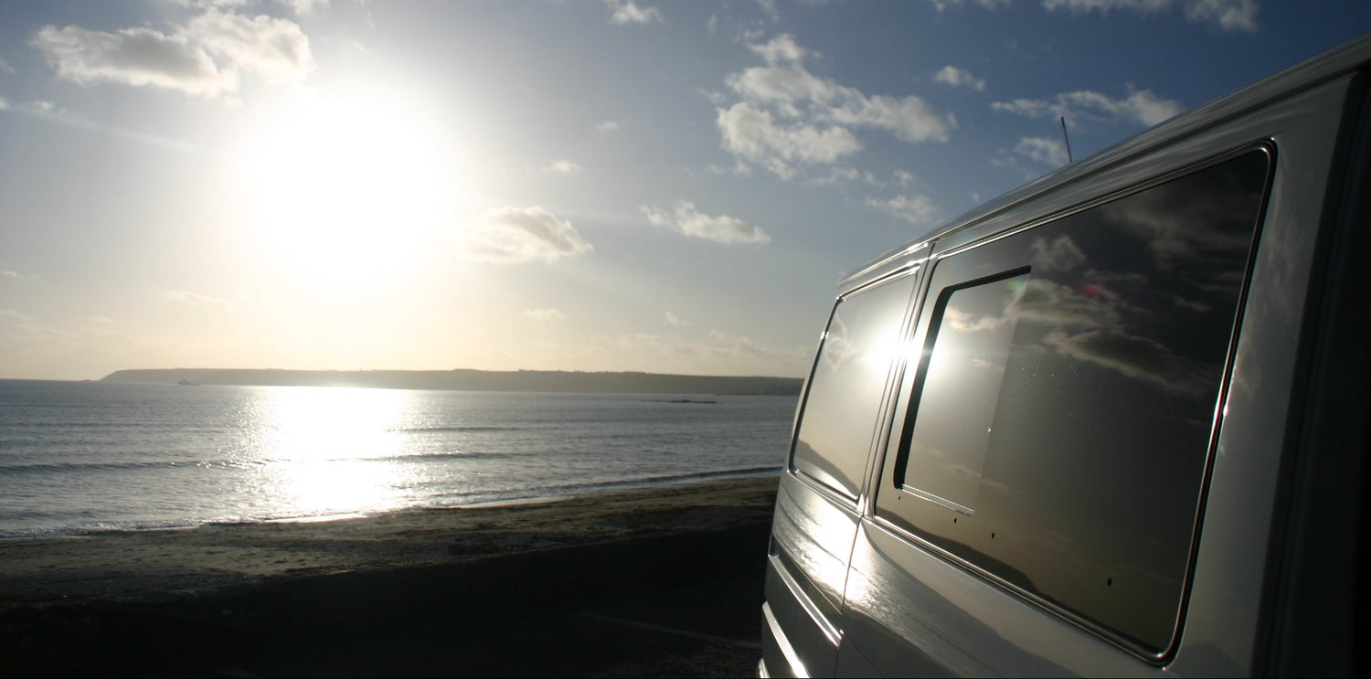 Volkswagen T4 van parked by the ocean in Cornwall with a sunset in the background